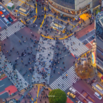 Aerial view of Shibuya Crossing in Tokyo, showcasing a bustling intersection filled with pedestrians and vehicles.