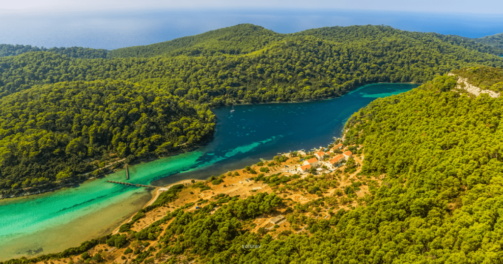 Aerial view of Mljet National Park in Croatia, showcasing lush green forests, turquoise waters, and a quaint village along the shoreline.