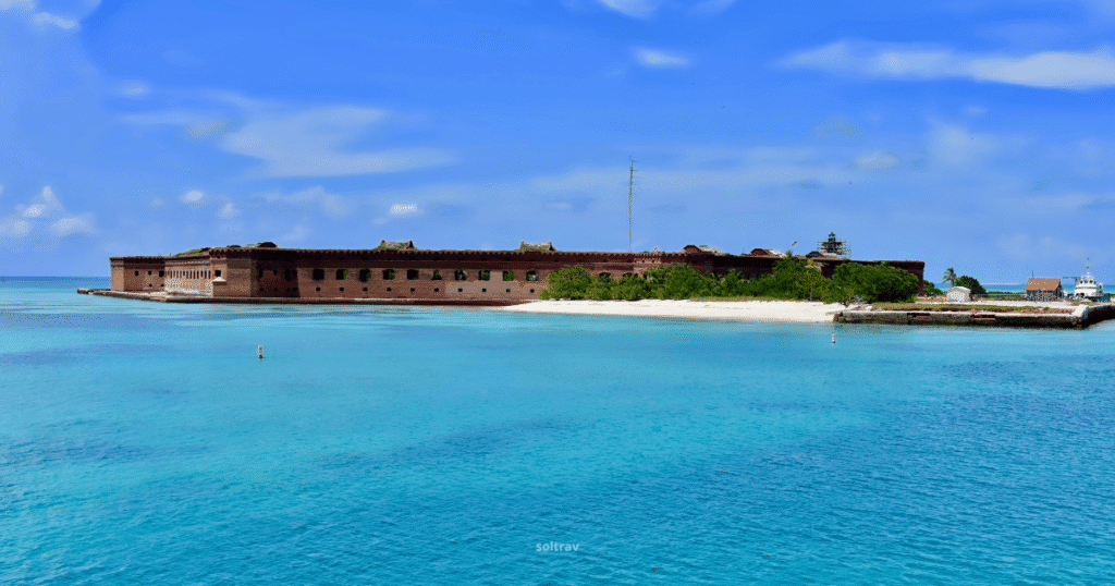 View of Fort Jefferson in Dry Tortugas National Park, Florida, surrounded by turquoise waters and a clear blue sky.