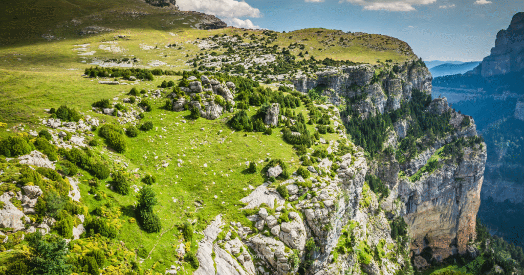 A breathtaking view of Parque Nacional Ordesa y Monte Perdido in Spain, showcasing dramatic cliffs and lush greenery under a clear blue sky.