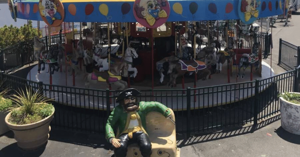 A colorful carousel at Adventurer's Amusement Park in New York, featuring a pirate statue in the foreground.