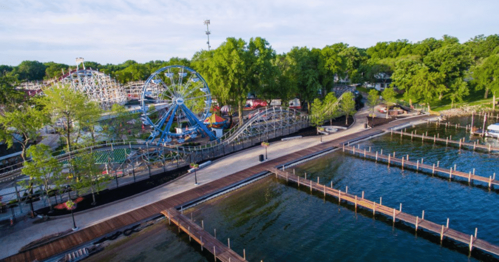 Aerial view of Arnolds Park Amusement Park in Iowa, featuring a roller coaster, Ferris wheel, and a scenic waterfront.