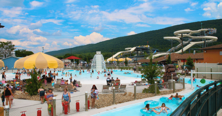 A vibrant water park scene at DelGrosso's Park in Pennsylvania, featuring water slides and a large pool filled with visitors.