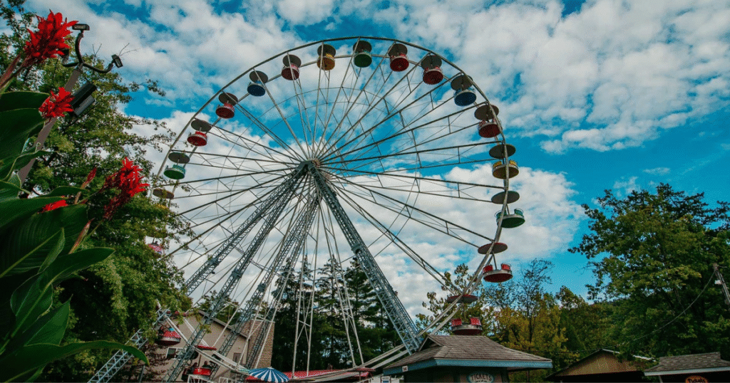 A close-up view of the Ferris wheel at Knoebels Amusement Resort in Pennsylvania, surrounded by greenery and a blue sky.